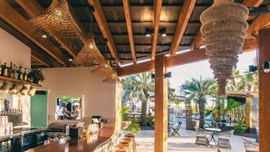 Un espace bar avec des tabourets en bois, un comptoir et des luminaires suspendus.
