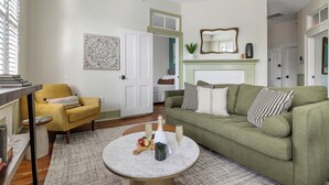 Un salon avec un canapé vert, un fauteuil jaune, une table basse en marbre et une cheminée.