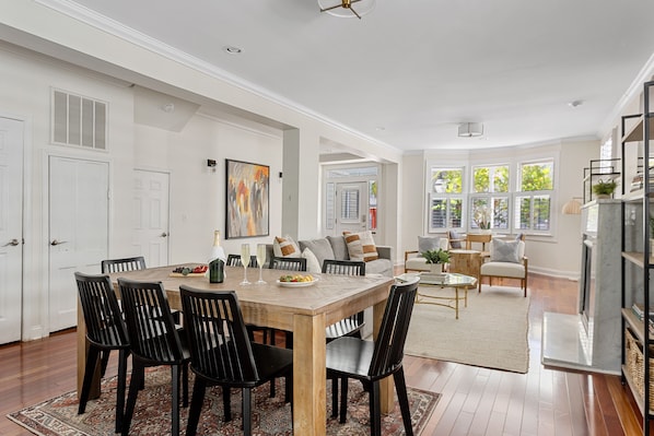 A spacious dining area with a wooden table and chairs, a sofa set, and a fireplace.
