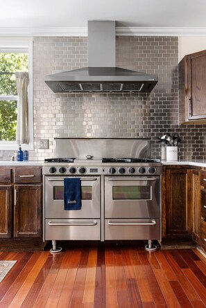 A kitchen with a stainless steel stove, double oven, and a large range hood.