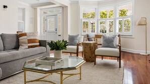 Ein gemütliches Wohnzimmer mit einem grauen Sofa, einem Glastisch und Holzstühlen.