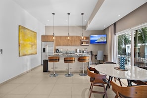 A modern kitchen with a central island, bar stools, and a dining table with chairs.
