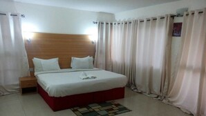 Una habitación de hotel con una cama grande, un cabecero de madera, una mesita de noche y una pequeña mesita auxiliar.