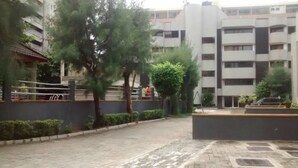Un edificio residencial con varios balcones, un patio empedrado y algunas áreas verdes.
