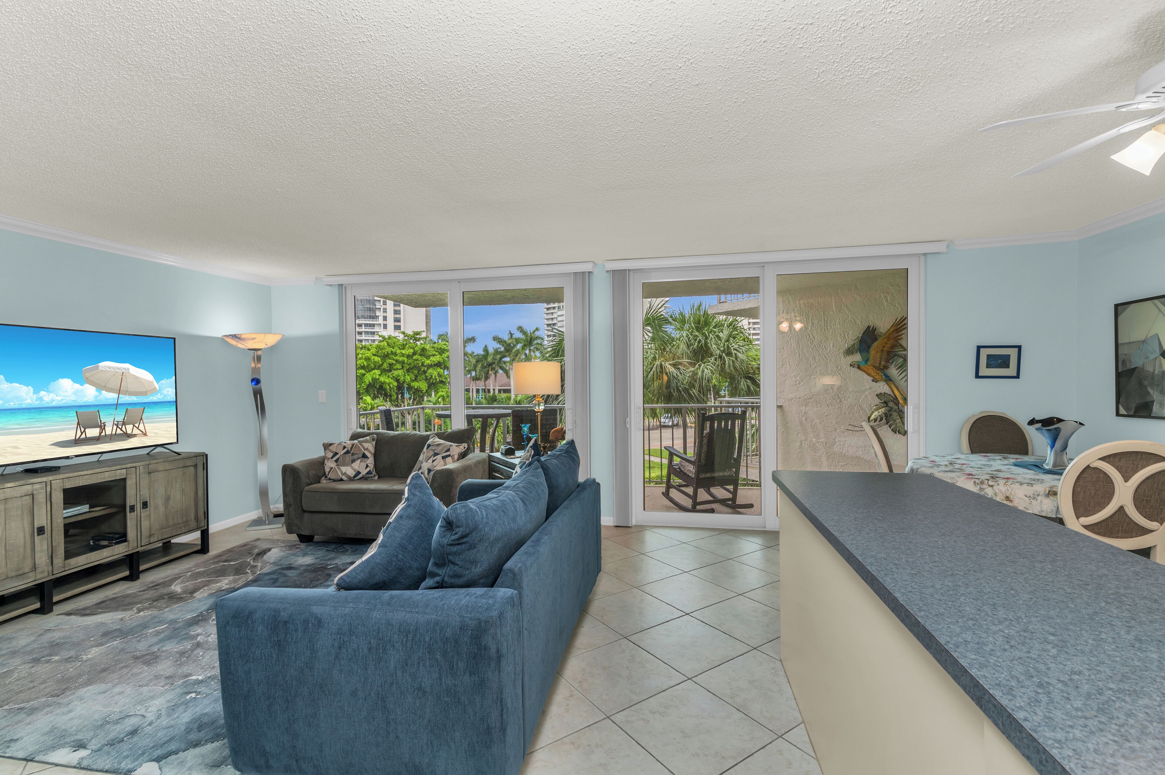 A living room with a TV, sofa, and a balcony with outdoor furniture.