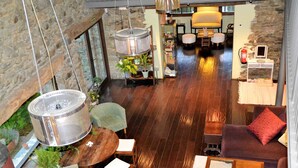 A spacious lobby with a stone wall, wooden flooring, and a seating area with a round table and chairs. - Hotel Cruells (Planoles)