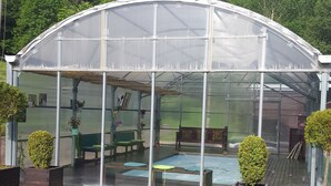 A greenhouse with a glass roof, a pool, and seating areas. - Hotel Cruells (Planoles)