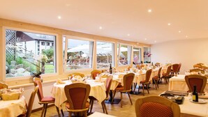 Un restaurante con varias mesas y sillas, amplias ventanas que ofrecen vistas al espacio exterior.