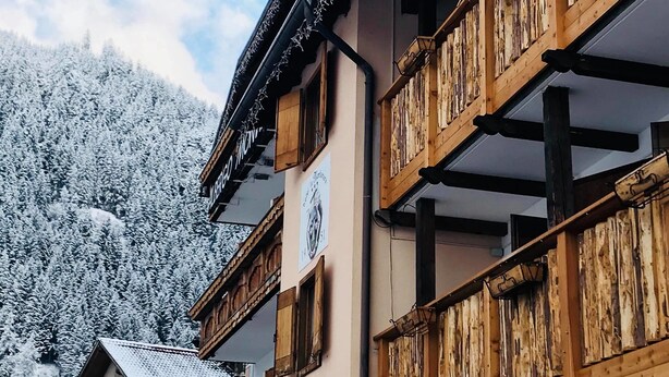 Un edificio de madera tradicional con balcones, con una imponente montaña nevada de fondo.