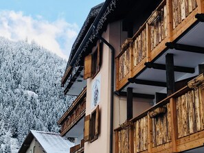 Un edificio de madera tradicional con balcones, con una imponente montaña nevada de fondo.