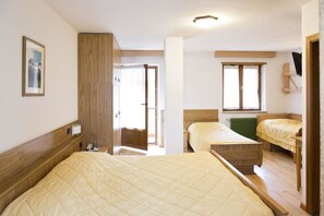 A bedroom with two beds, wooden headboards, a green radiator, and a framed picture on the wall.