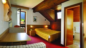 Un dormitorio con cama de madera, un escritorio, una silla y una ventana con cortinas.