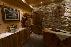 Un interior de madera con paredes de piedra, armarios de madera y un jarrón de flores.