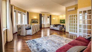 A spacious living area with a dining table and chairs, a red sofa, and a large rug.