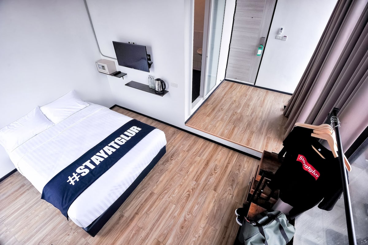 Habitación de hotel con cama, televisión, minibar y puerta corredera al baño.