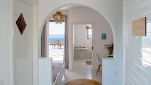 A hallway leading to a balcony with a view of the sea, a dining area with a table and chairs, and a small office space. - Pefkides Aegina Apartments (Aegina)