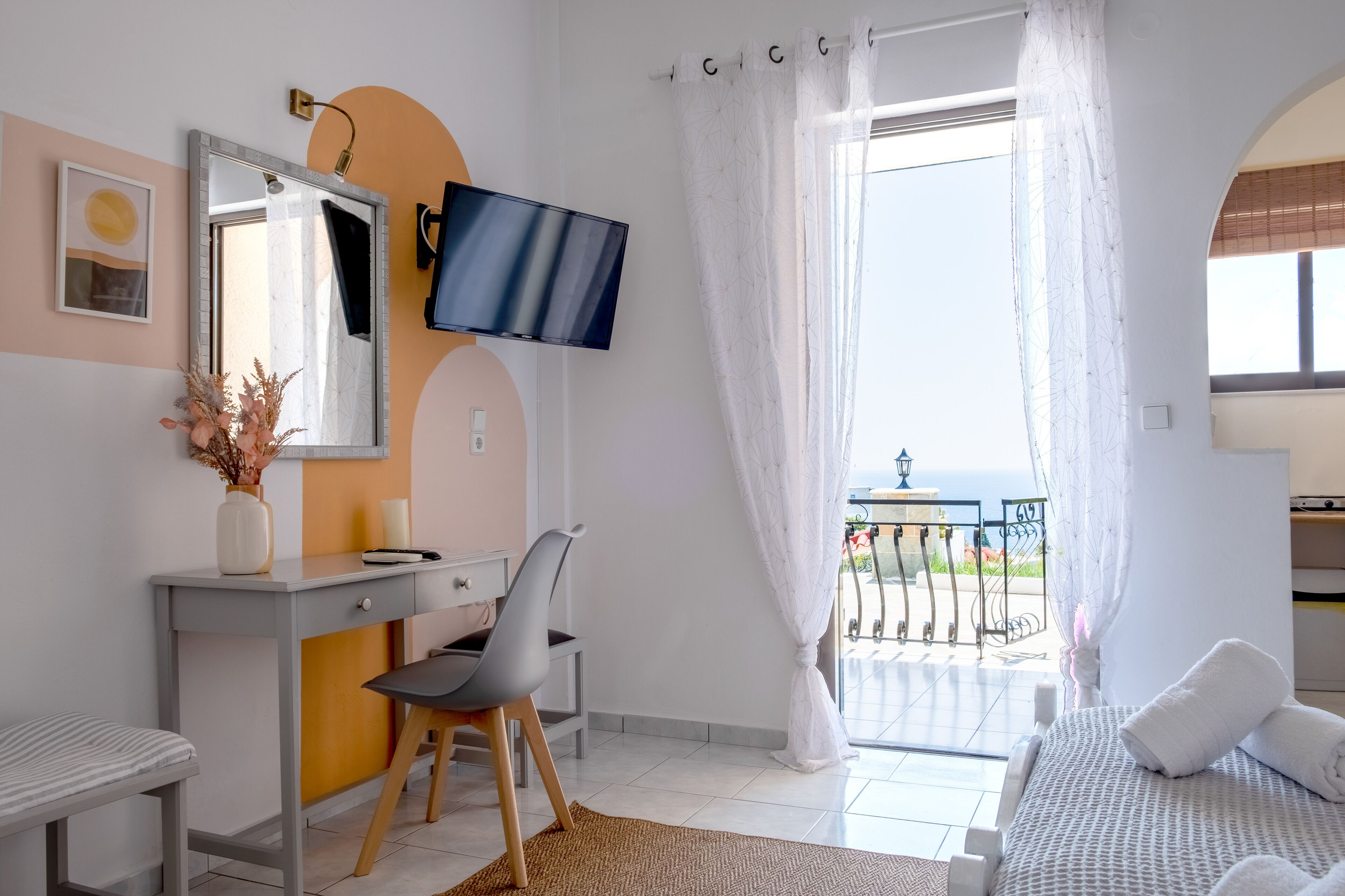 Camera d'albergo con un letto, una scrivania con una sedia, una televisione, una finestra con tende e vista esterna.