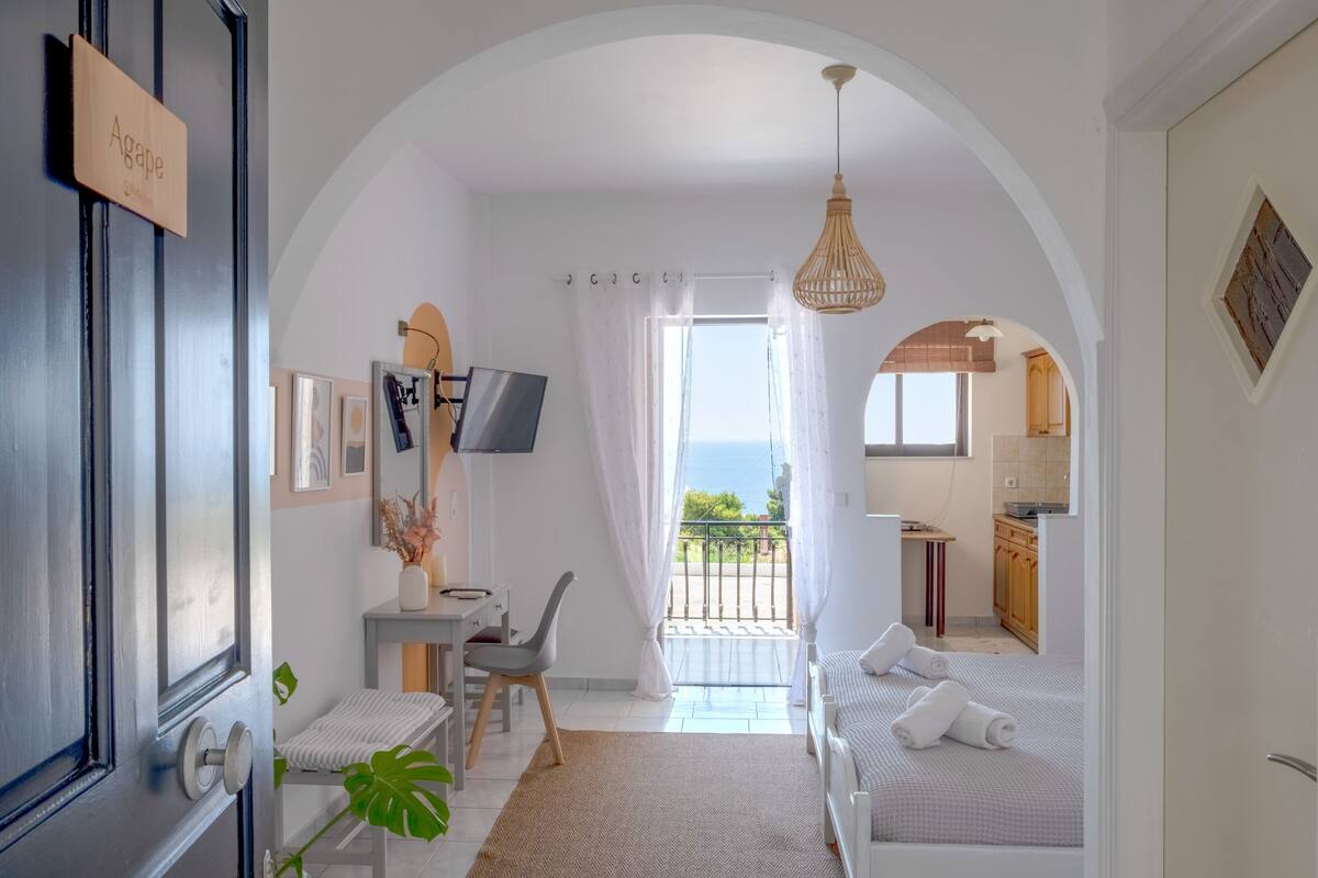 Un dormitorio moderno con balcón, escritorio y televisor.