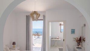 A modern hotel room with a bed, a desk, and a view of the sea. - Pefkides Aegina Apartments (Aegina)