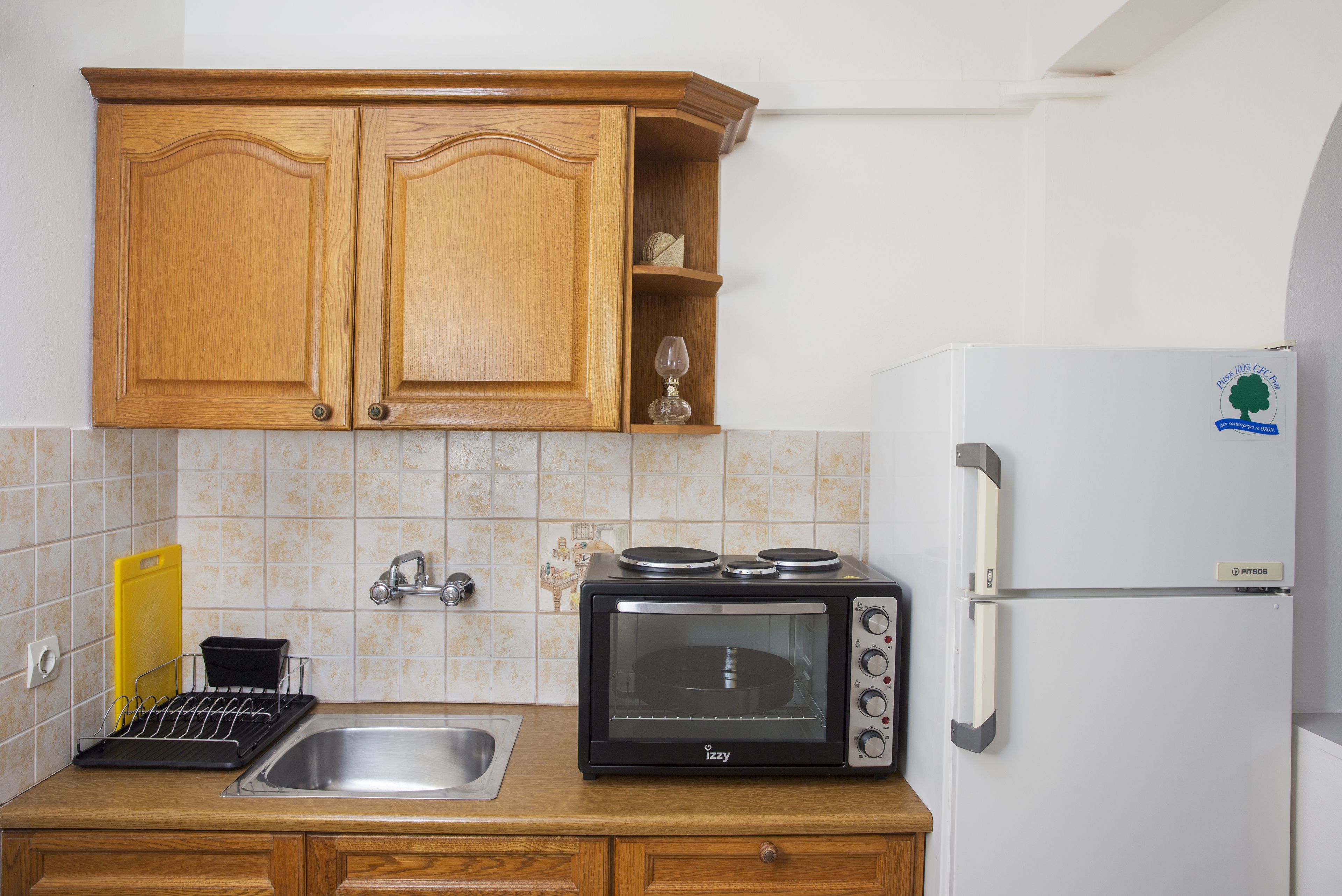 A kitchen with wooden cabinets, a built-in microwave, a sink, and a refrigerator.