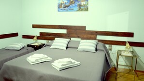 A hotel room with two beds, a wooden headboard, a painting on the wall, and a bedside table with a lamp.