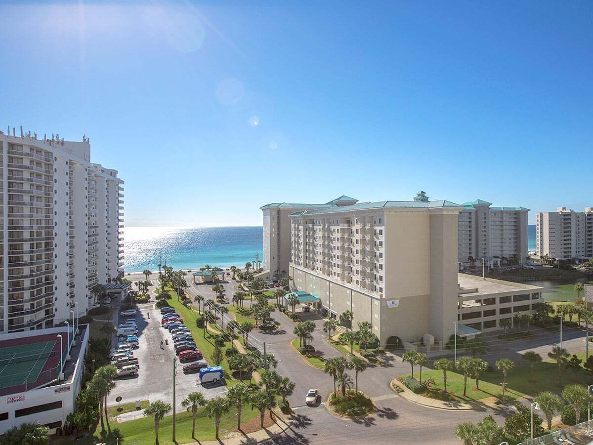 A hotel with multiple floors, a parking lot, and a view of the ocean.