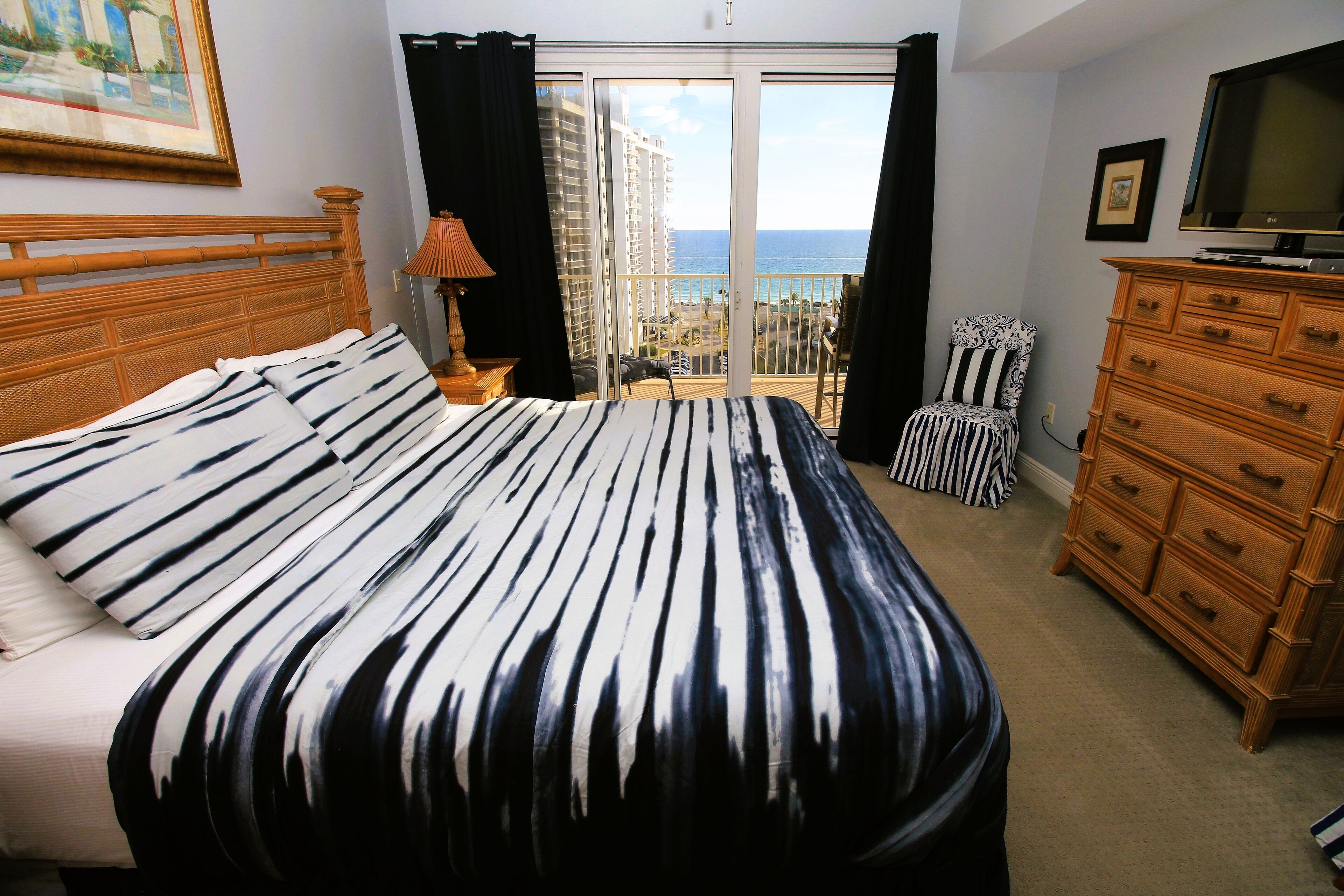 Une chambre d’hôtel avec un grand lit, une commode, une télévision et un balcon offrant une vue sur la ville.
