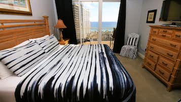 Une chambre d’hôtel avec un grand lit, une commode, une télévision et un balcon offrant une vue sur la ville.