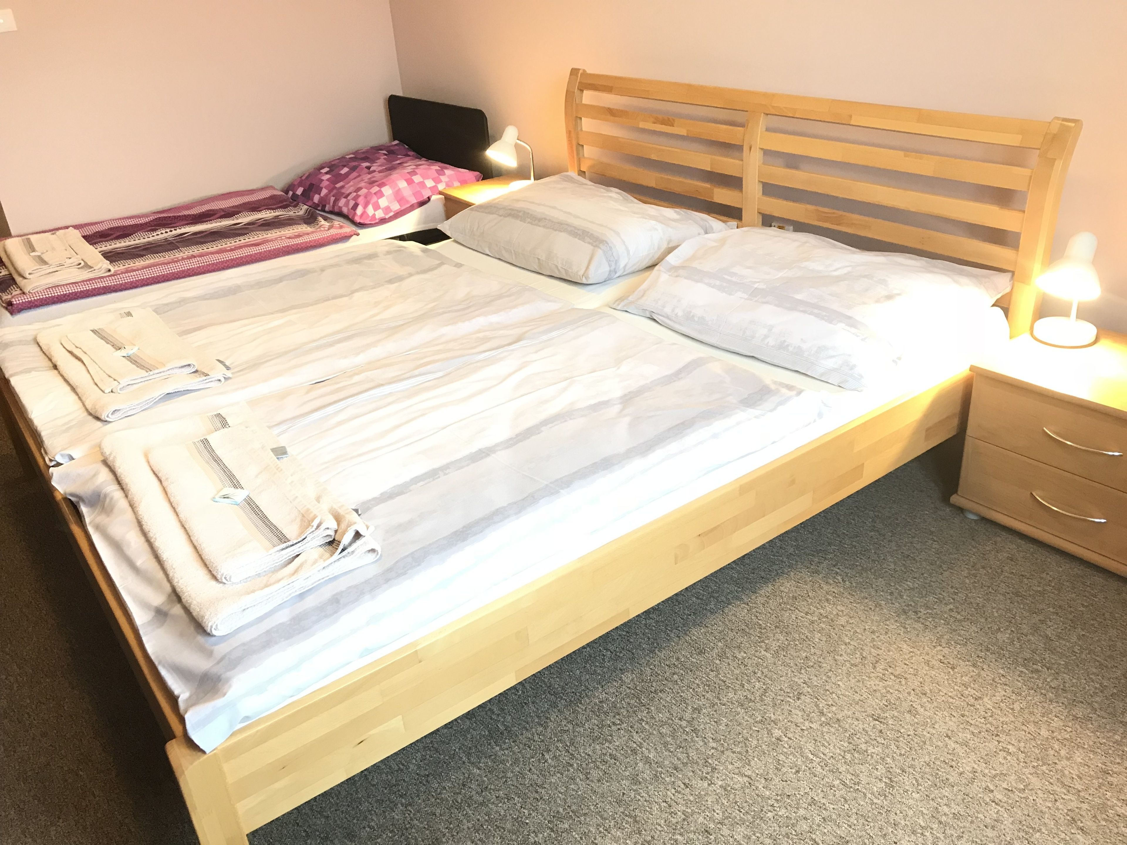A double bed with a wooden headboard and two bedside tables, each with a lamp.