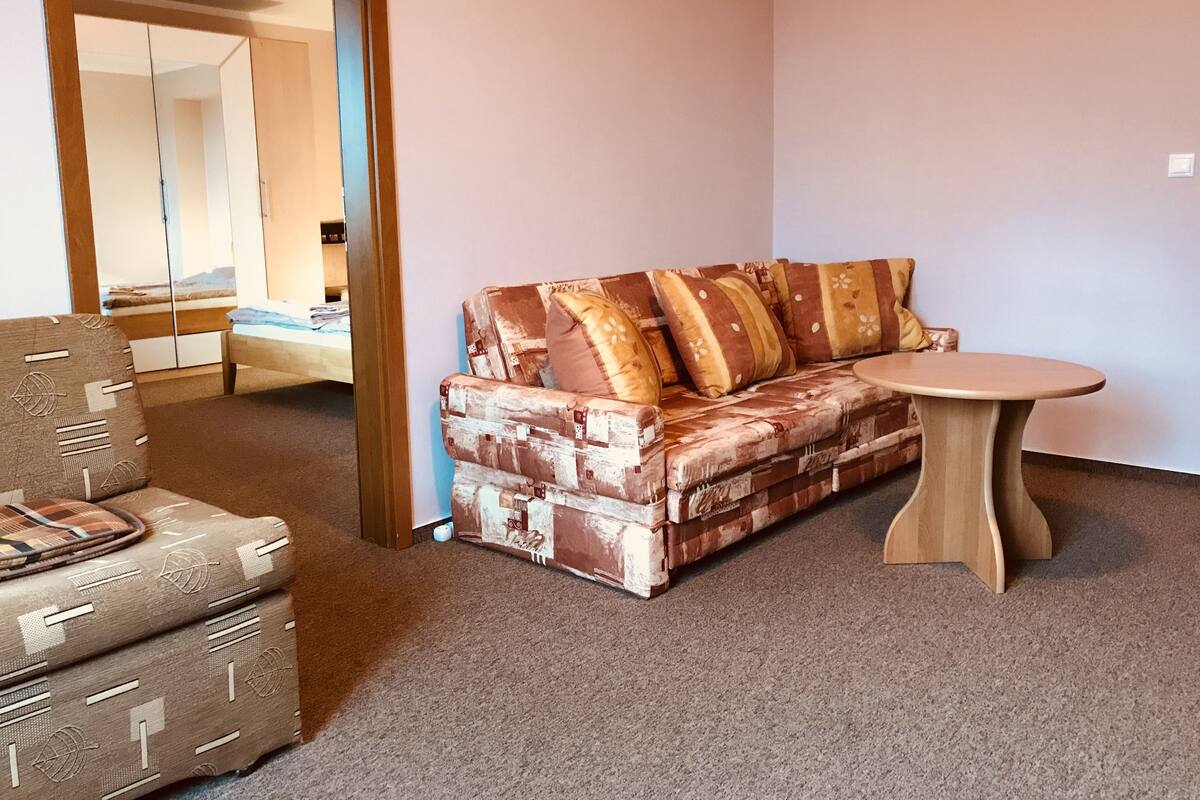 A room with a patterned sofa, a small round table, and a patterned armchair.
