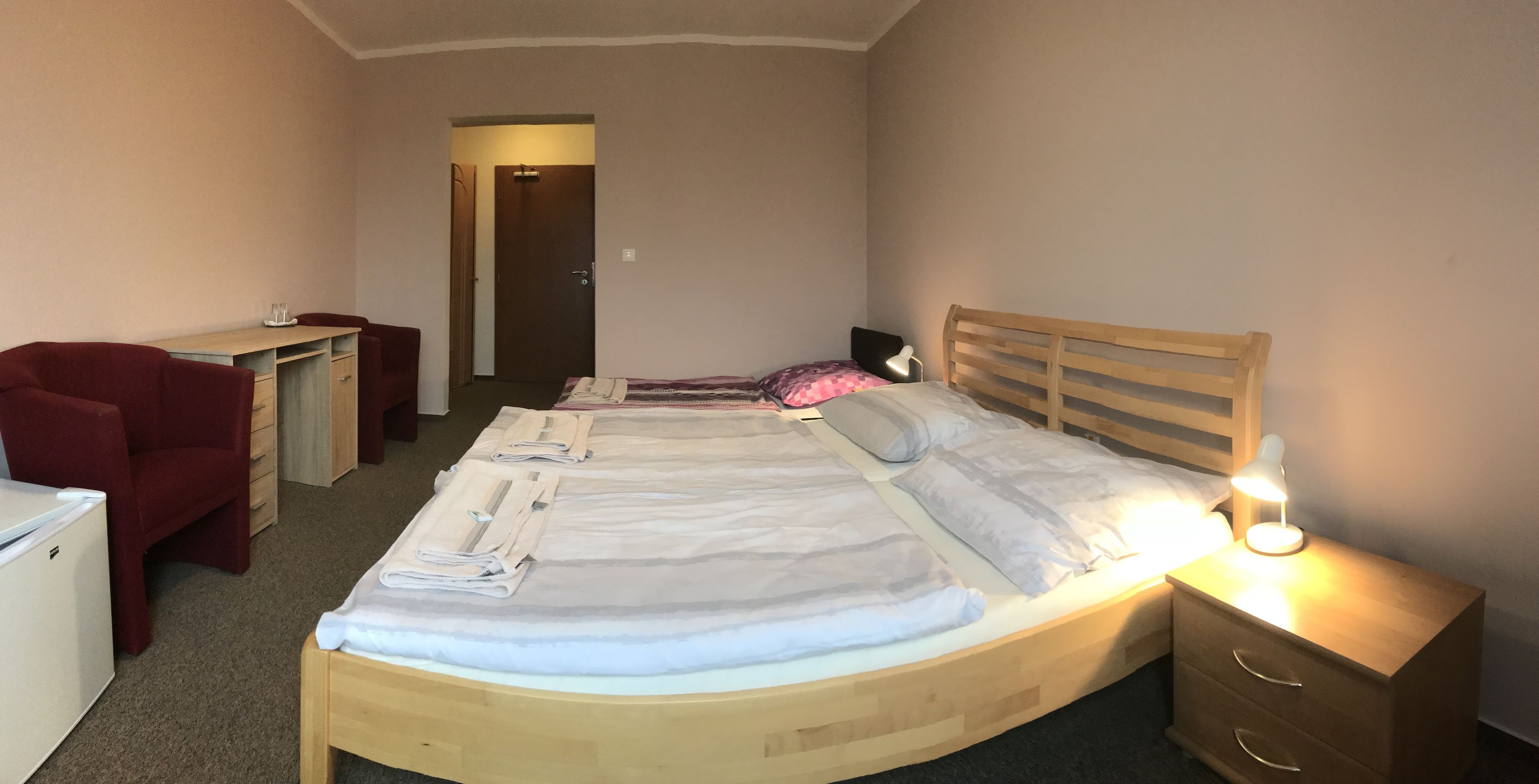 Een netjes ingerichte hotelkamer met een bed, een bureau, een stoel en een dressoir.