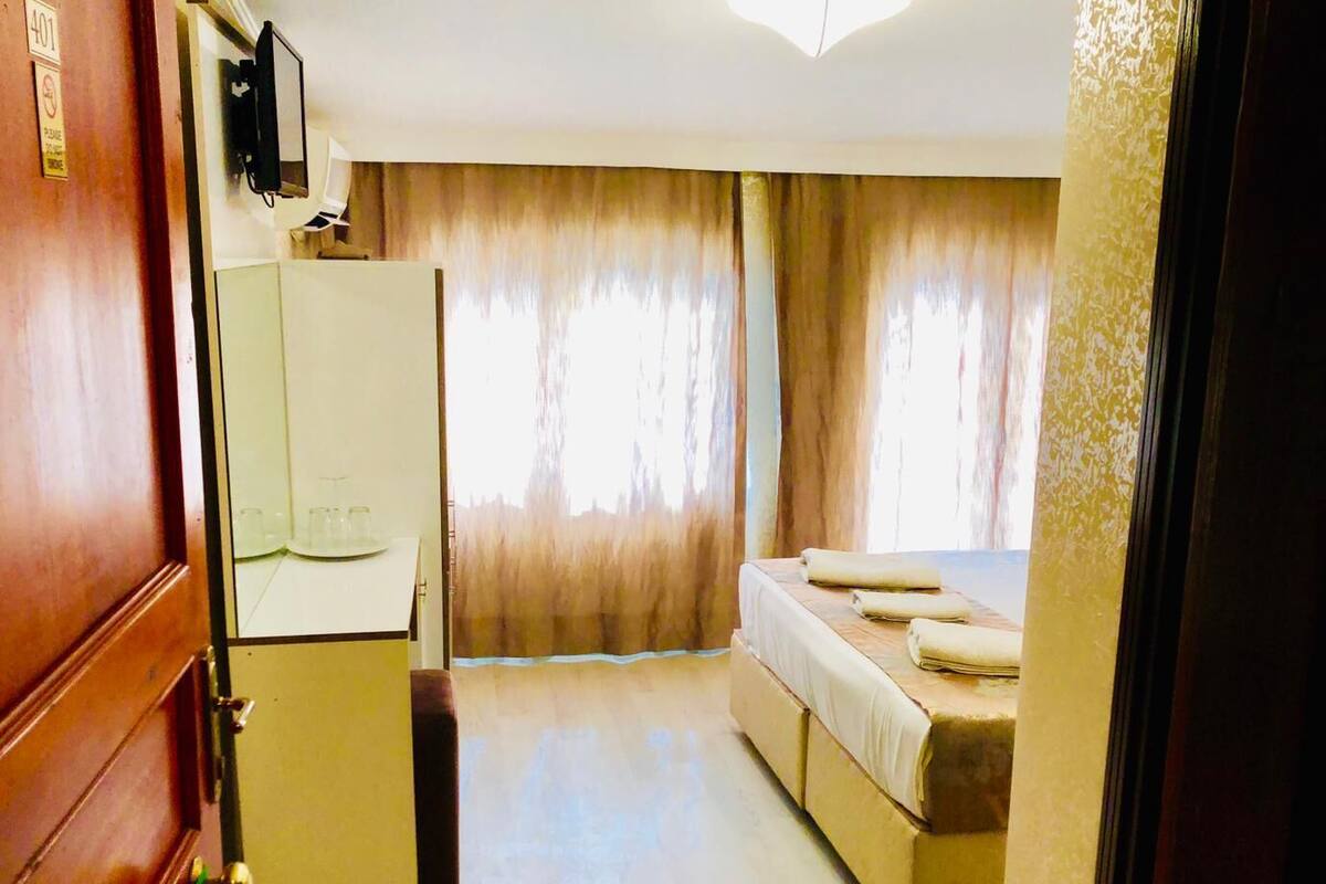 A compact hotel room with a bed, a small desk, and a mirror.