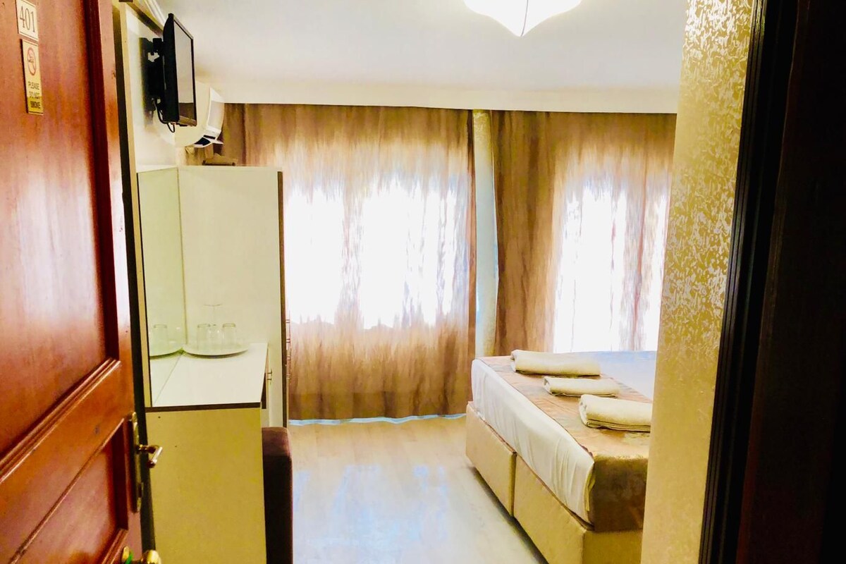 Habitación de hotel pequeña con cama, un escritorio y un espejo.