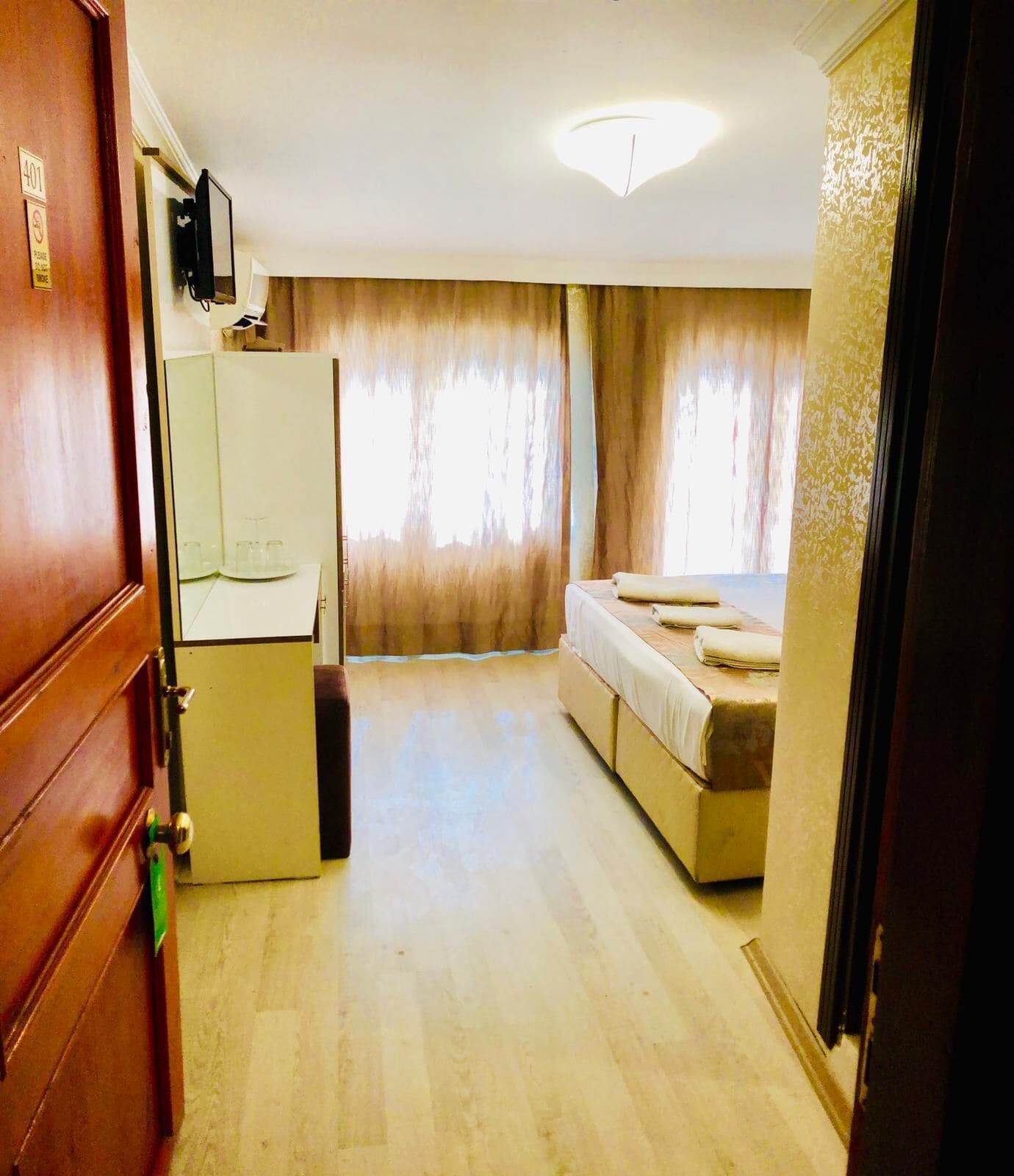 Habitació d'hotel compacta amb llit, escriptori petit i mirall.
