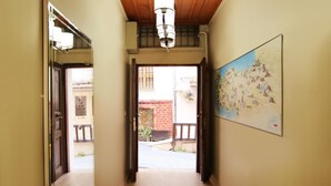 Un pasillo con techo de madera, un mapa en la pared y una puerta que da a un espacio exterior.