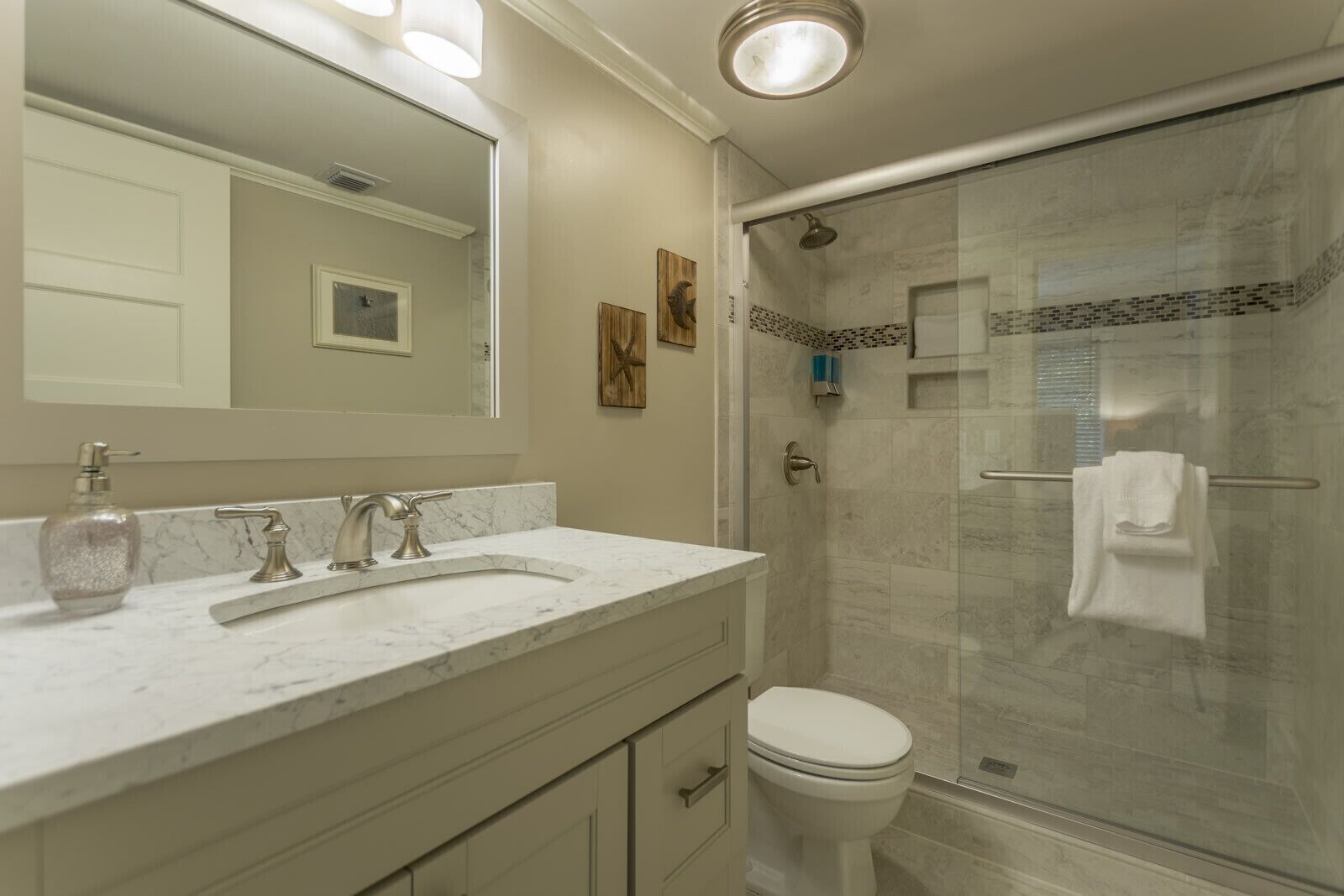A bathroom with a marble sink, a toilet, and a glass-enclosed shower.