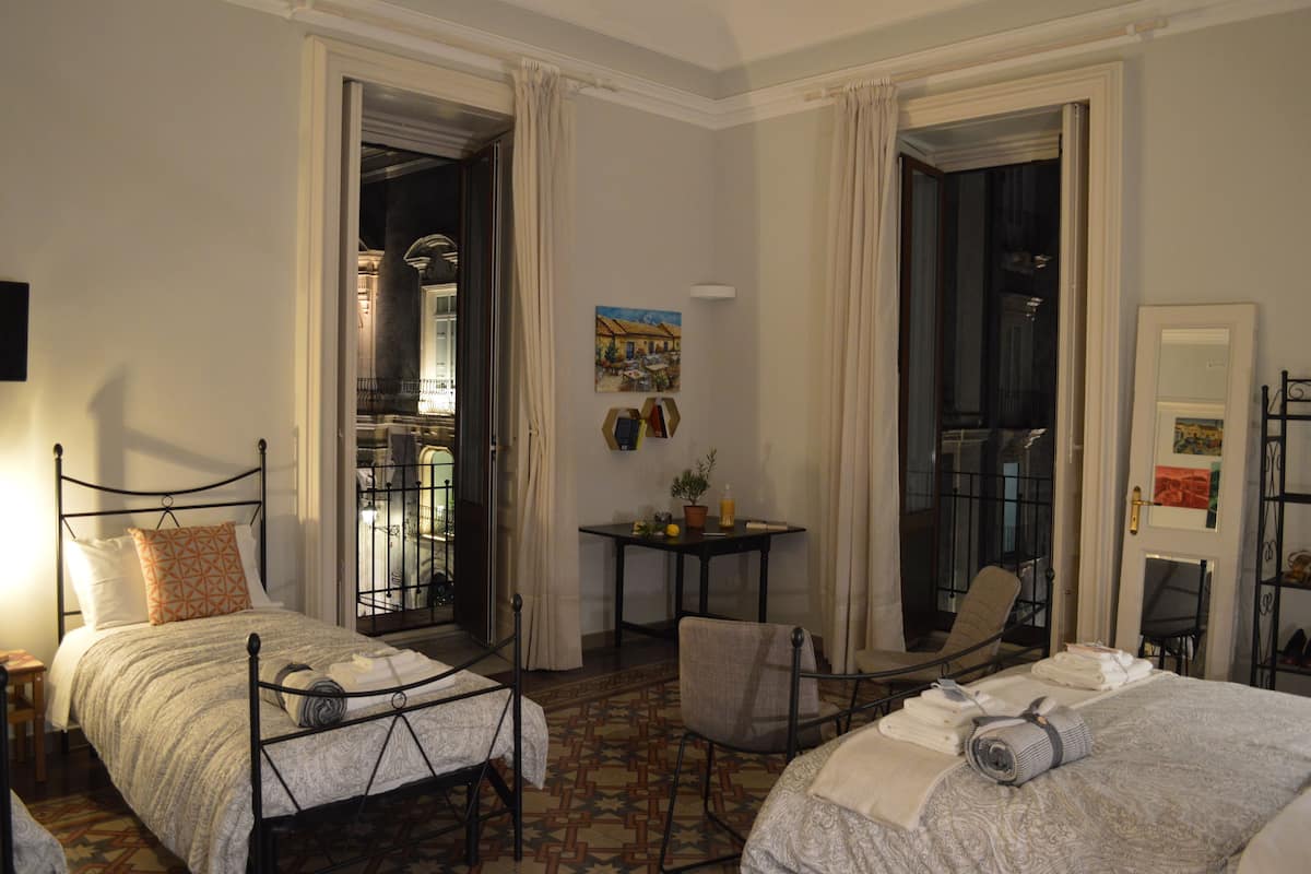 A hotel room with two beds, a small table with a potted plant, and a chair.