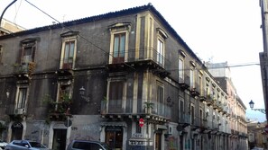 A multi-story building with balconies, a storefront, and a street sign.