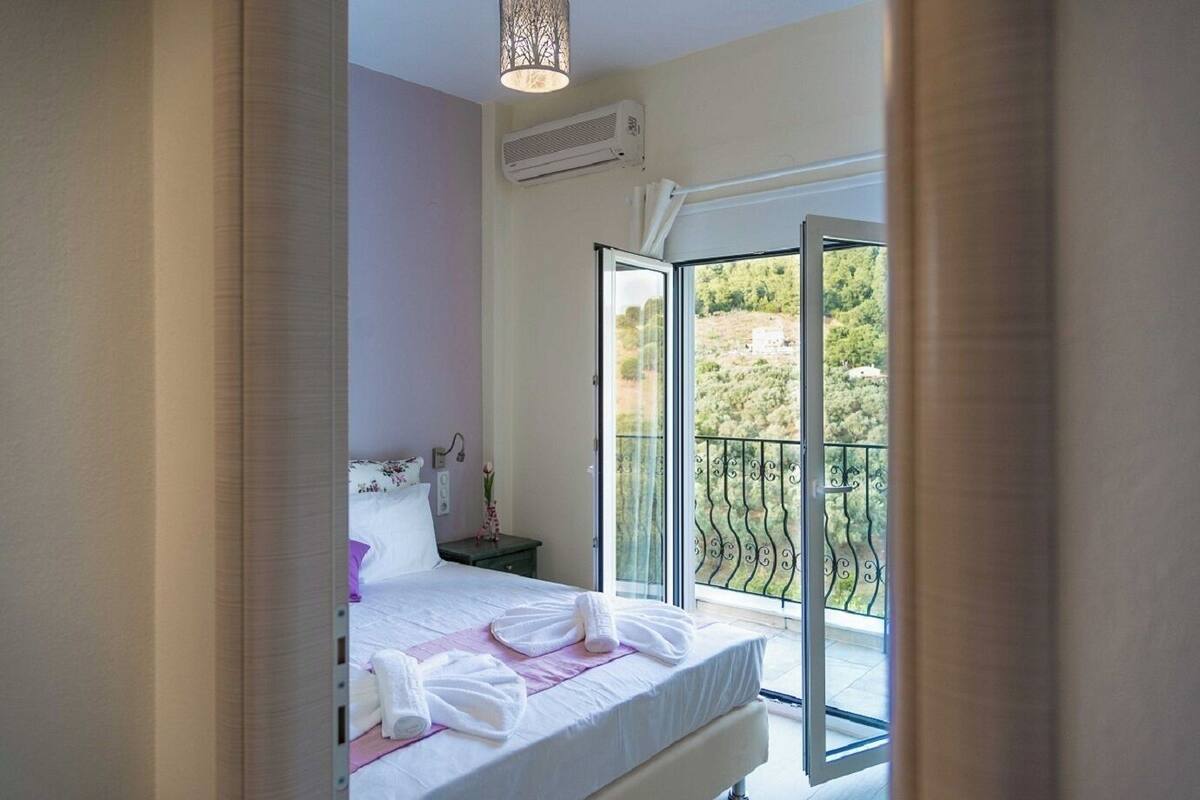 A bedroom with a bed, a nightstand, and a view of a balcony with a railing.