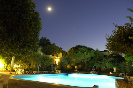 Una piscina al aire libre, sombrillas, sillones reclinables de piscina