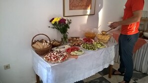 Une table de buffet garnie de différents plats et une personne qui sert les aliments.