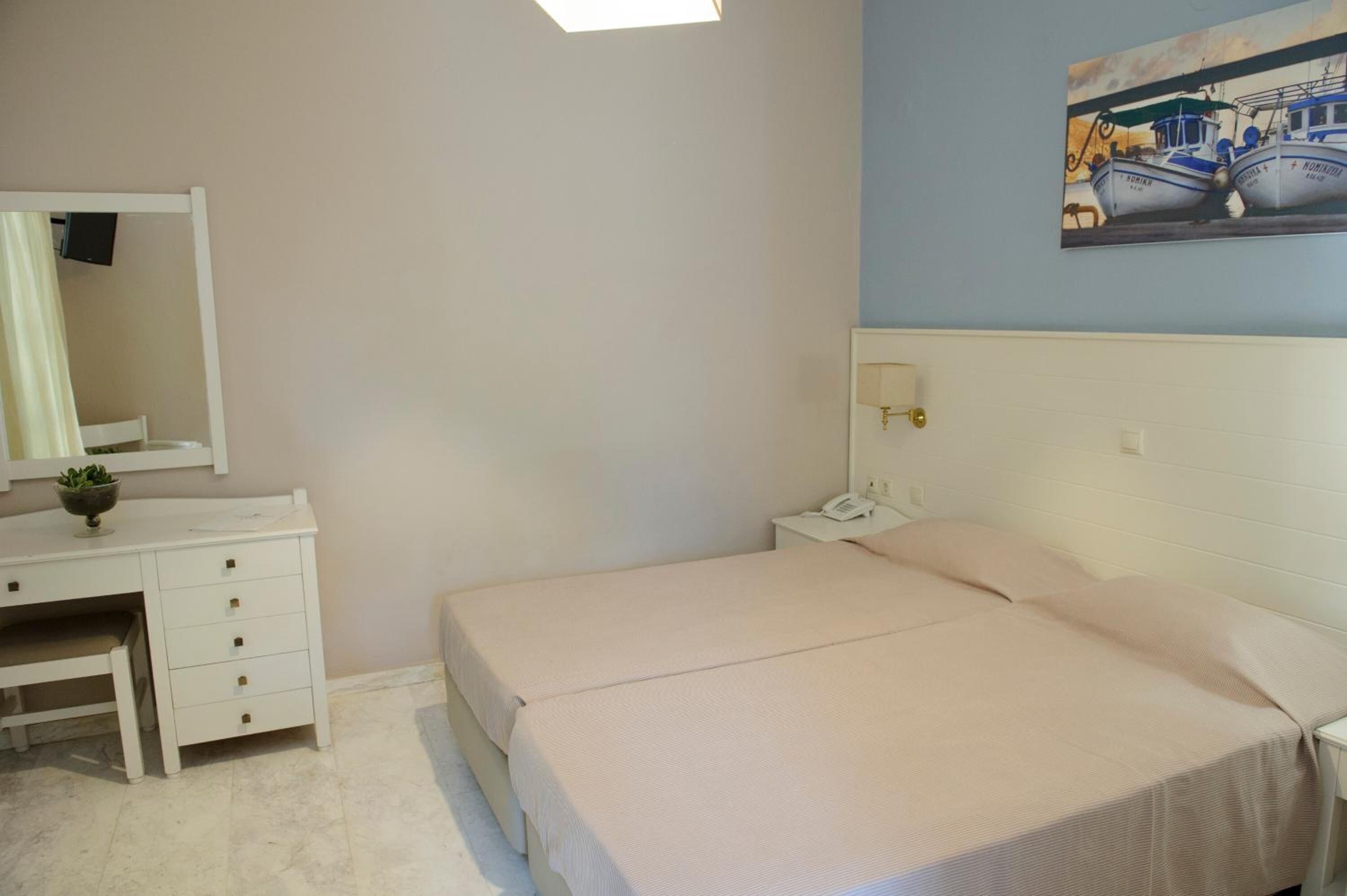 Una camera da letto con un letto, un comodino, uno specchio e una scrivania con cassetti.
