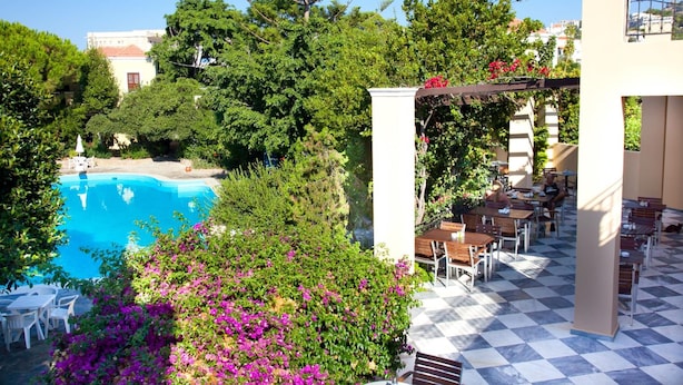 A rooftop pool area with a checkered floor, surrounded by lush greenery and a pergola with flowers. - Kalydna Island Hotel (Kalymnos)