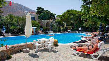A poolside area with lounge chairs, a table, and umbrellas.