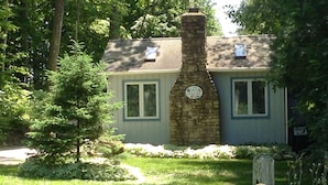 A stone chimney, a window, and a sign on a building surrounded by greenery. - Retro, Cozy Cottage - Peninsula St. Park, Family/Pet Friendly - OPEN year around (Fish Creek)