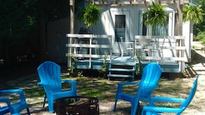 A small wooden cabin with a porch, two blue Adirondack chairs, and a fire pit. - Retro, Cozy Cottage - Peninsula St. Park, Family/Pet Friendly - OPEN year around (Fish Creek)