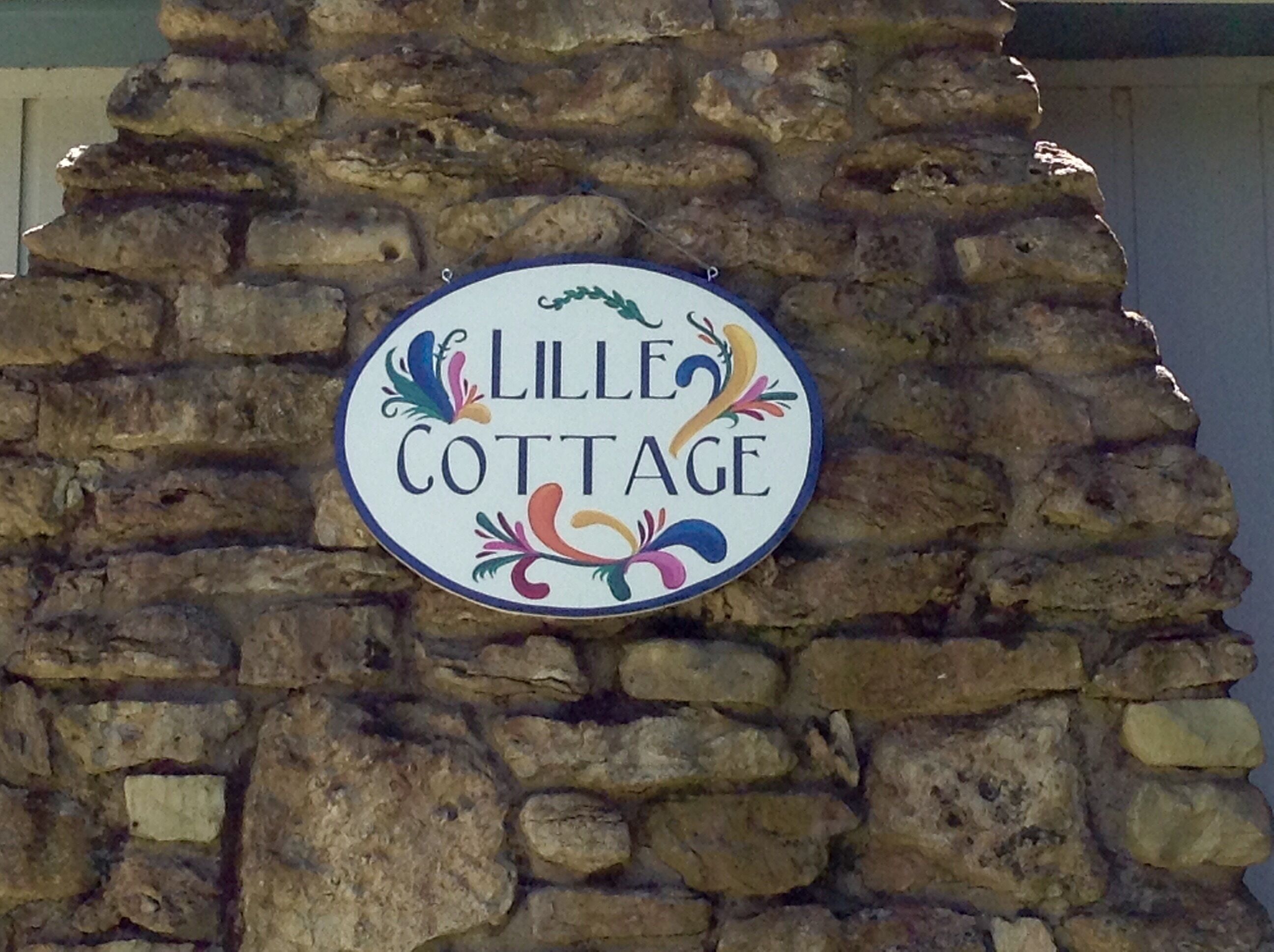 A sign for 'Lille Cottage' mounted on a stone wall.