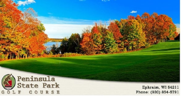 A golf course with autumn foliage, a clear sky, and a body of water in the background. - Retro, Cozy Cottage - Peninsula St. Park, Family/Pet Friendly - OPEN year around (Fish Creek)