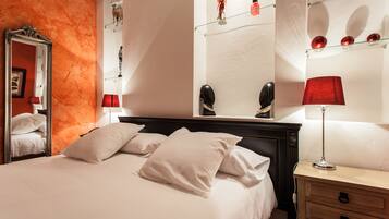 A hotel room with a bed, a nightstand, a mirror, and a wall with decorative items.