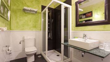 Un bagno con doccia vetrata, un water e un lavabo con piano in marmo.